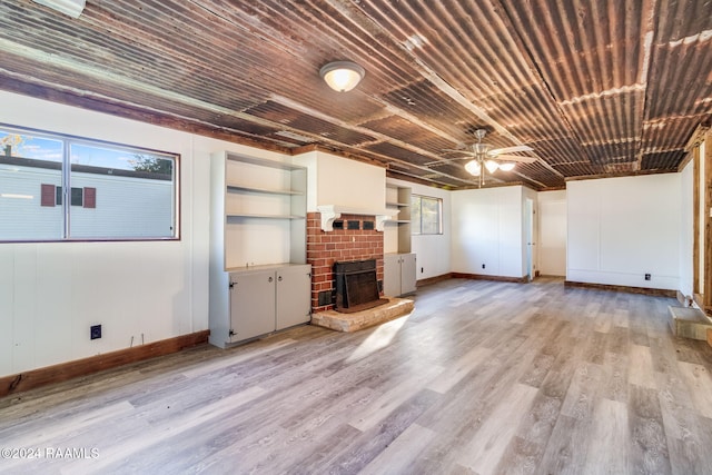 unfurnished living room featuring a fireplace, ceiling fan, and light hardwood / wood-style flooring