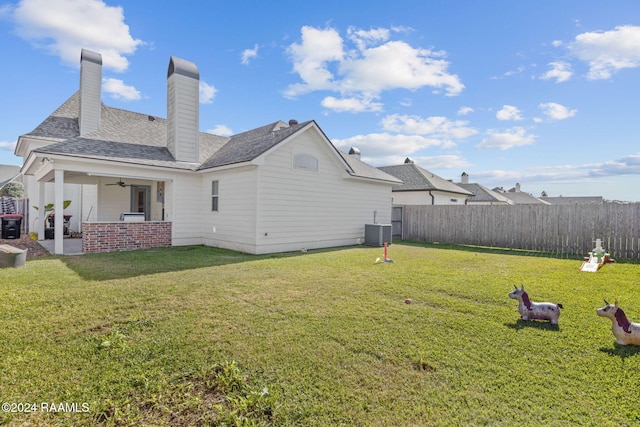 rear view of house featuring central AC unit, ceiling fan, and a yard