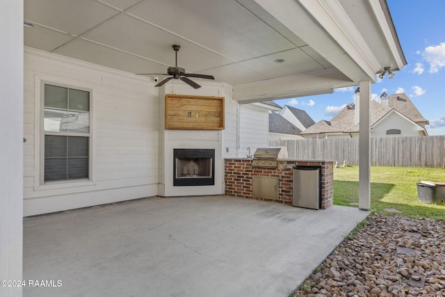 view of patio featuring ceiling fan, exterior kitchen, an outdoor fireplace, and grilling area