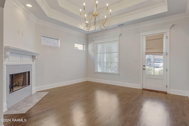 unfurnished living room with a chandelier, hardwood / wood-style flooring, a raised ceiling, and ornamental molding