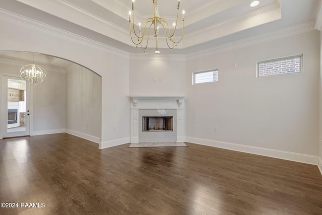 unfurnished living room featuring a tray ceiling, crown molding, a fireplace, and a chandelier