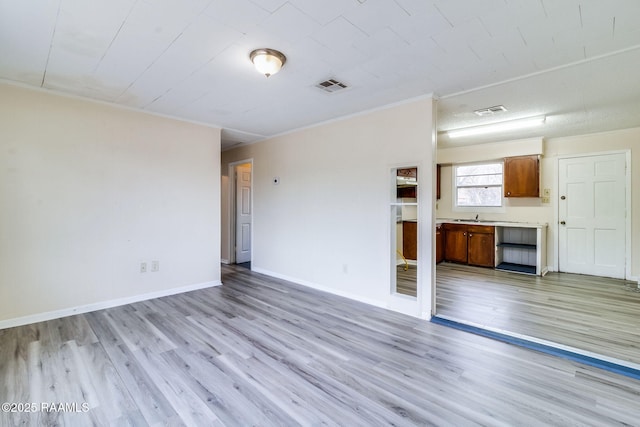 unfurnished living room featuring light wood-type flooring and crown molding