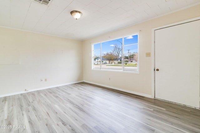 spare room featuring light wood-type flooring and ornamental molding