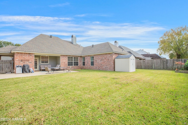 rear view of property with a patio area, a yard, and a storage shed