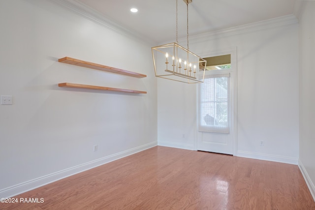 empty room featuring hardwood / wood-style floors, crown molding, and a chandelier