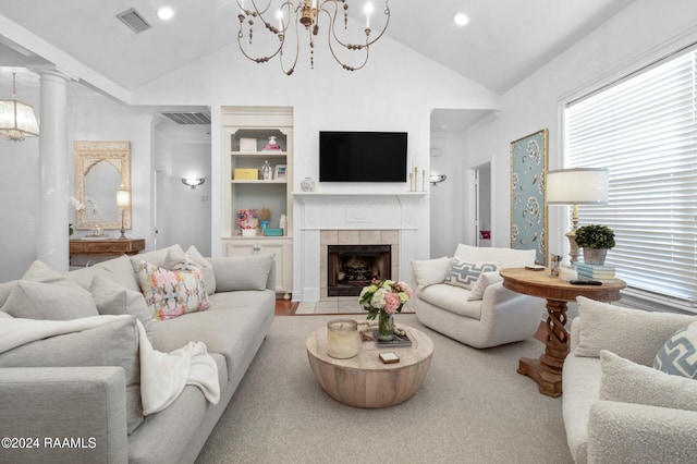 living room featuring a tile fireplace, a chandelier, ornate columns, and lofted ceiling