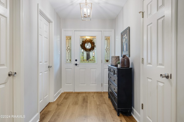 doorway featuring a chandelier and light hardwood / wood-style flooring