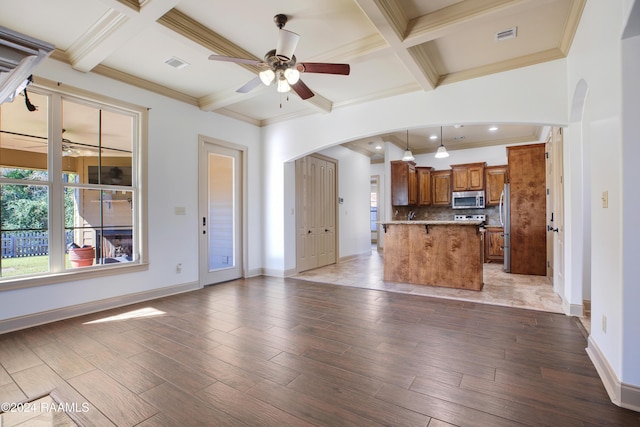 unfurnished living room featuring coffered ceiling, beam ceiling, ornamental molding, and light hardwood / wood-style flooring