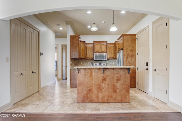 kitchen featuring pendant lighting, a kitchen island, crown molding, and appliances with stainless steel finishes