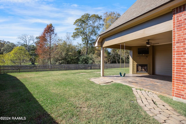 view of yard with ceiling fan, a patio, and exterior fireplace