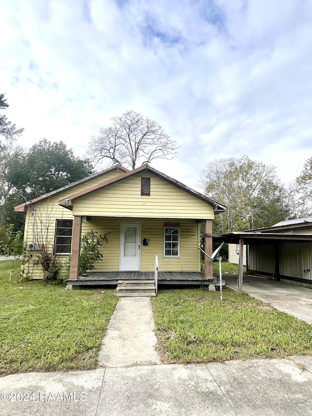 view of front facade featuring a front lawn, covered porch, and a carport