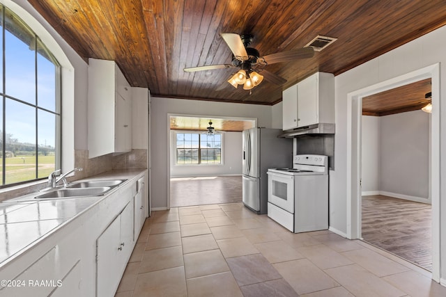 kitchen with electric stove, light tile patterned flooring, sink, and white cabinets