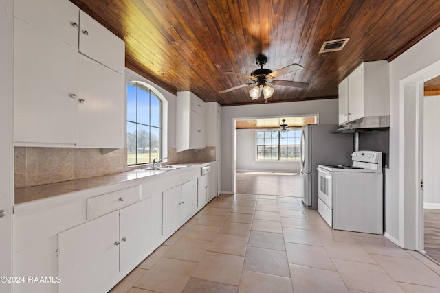 kitchen with light tile patterned flooring, white electric range oven, sink, white cabinetry, and tasteful backsplash