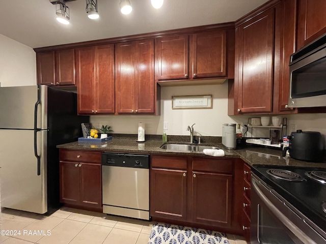 kitchen featuring dark stone counters, sink, light tile patterned floors, and stainless steel appliances