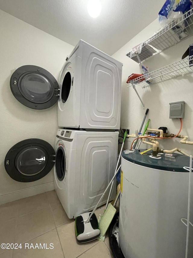 laundry area featuring light tile patterned flooring, gas water heater, and stacked washer and clothes dryer