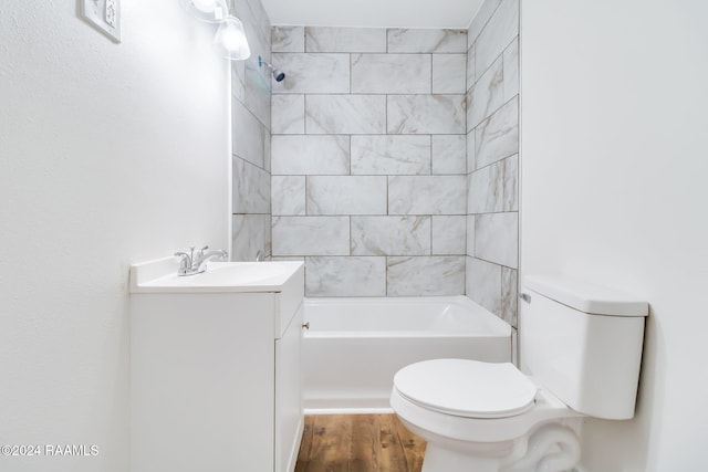 full bathroom with tiled shower / bath, hardwood / wood-style floors, vanity, and toilet