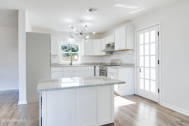 120 Oak Crest Dr, Lafayette, LA 70503 - kitchen with high end stainless steel range oven, under cabinet range hood, a chandelier, light wood finished floors, and white cabinets