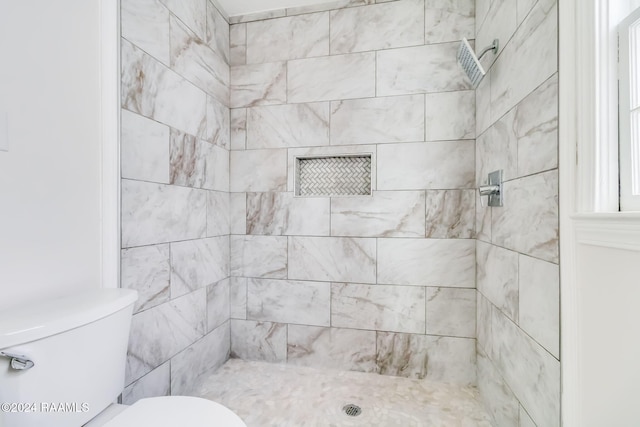 bathroom featuring tiled shower and toilet