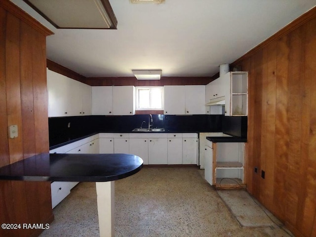 kitchen with white cabinets, backsplash, kitchen peninsula, and sink