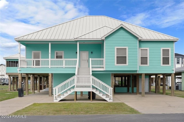 133 Lighthouse Ln, Lake Charles, LA 70607 - raised beach house featuring a carport, driveway, and a standing seam roof