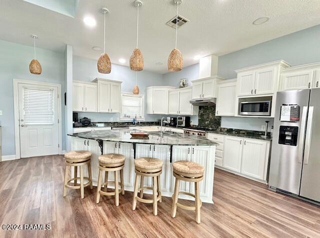 133 Lighthouse Ln, Lake Charles, LA 70607 - kitchen with stainless steel appliances, light wood-style floors, dark countertops, and a breakfast bar