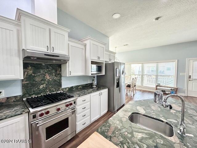 kitchen with dark stone countertops, white cabinetry, sink, and stainless steel appliances