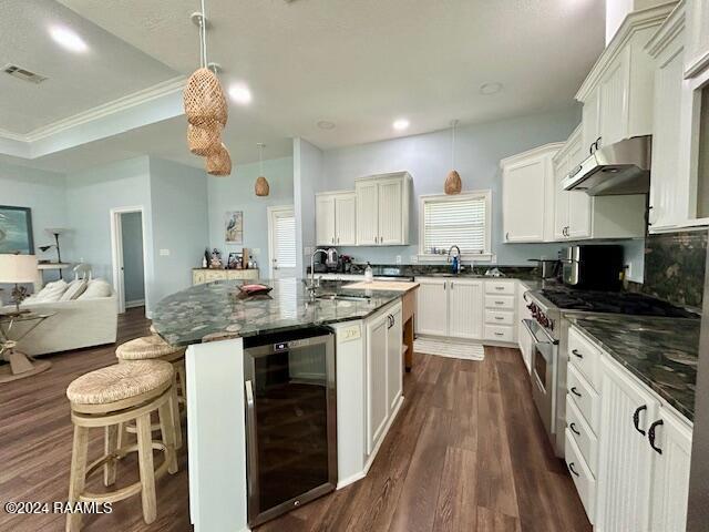 kitchen with hanging light fixtures, high end stainless steel range, dark hardwood / wood-style floors, ornamental molding, and beverage cooler