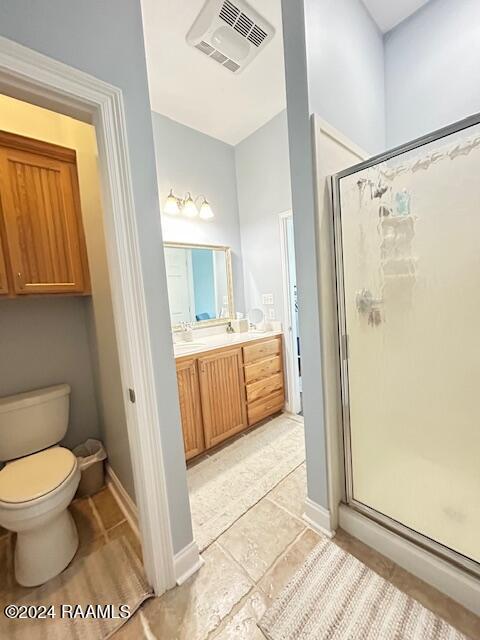 bathroom with tile patterned floors, vanity, toilet, and a shower with door