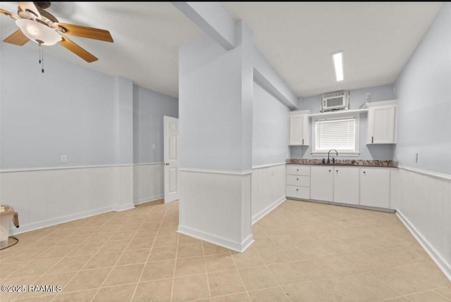 133 Lighthouse Ln, Lake Charles, LA 70607 - kitchen with wainscoting, white cabinetry, ceiling fan, a wall unit AC, and light tile patterned flooring