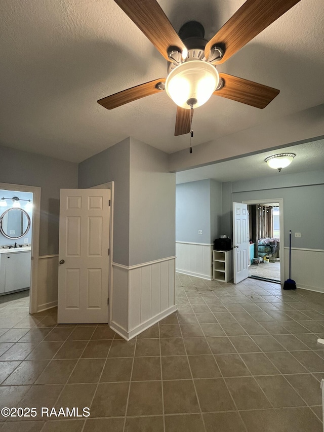 133 Lighthouse Ln, Lake Charles, LA 70607 - spare room featuring a wainscoted wall, ceiling fan, dark tile patterned floors, and a textured ceiling