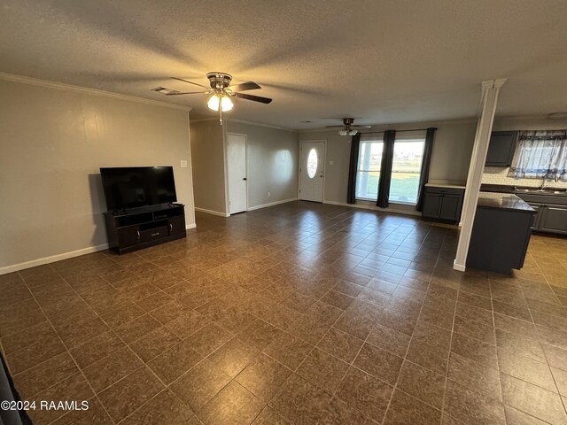 unfurnished living room featuring a textured ceiling, ceiling fan, ornamental molding, and sink