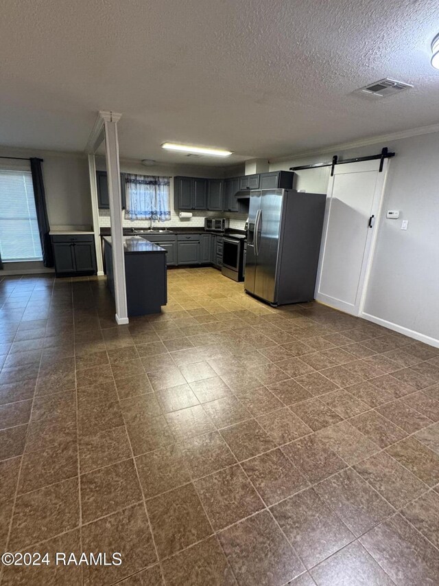 kitchen with sink, a barn door, a textured ceiling, gray cabinets, and appliances with stainless steel finishes