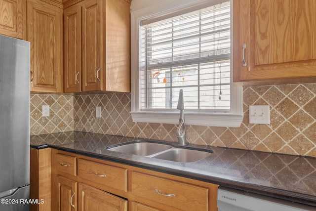 kitchen with white dishwasher, stainless steel fridge, sink, and tasteful backsplash