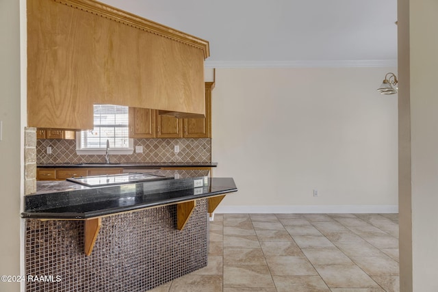 kitchen with black electric stovetop, backsplash, a breakfast bar, light tile patterned flooring, and ornamental molding