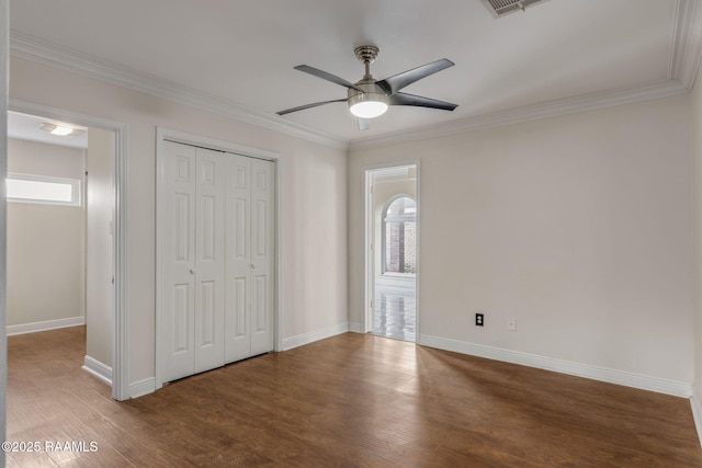 unfurnished bedroom with ceiling fan, dark wood-type flooring, a closet, and ornamental molding