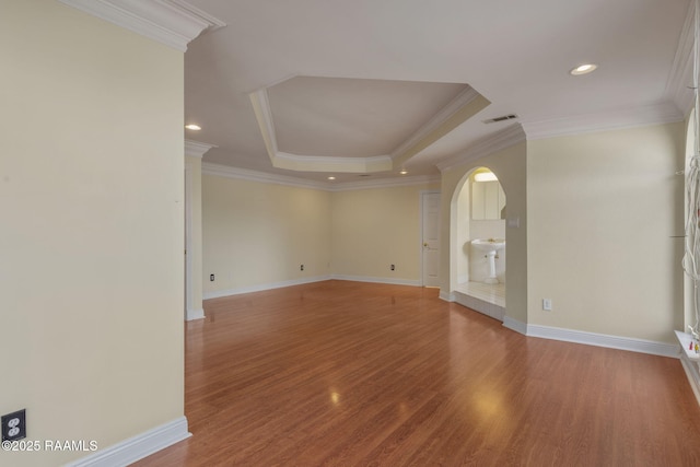 empty room with crown molding, a tray ceiling, and hardwood / wood-style flooring