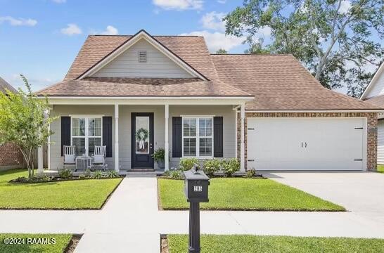 view of front of house featuring a front yard, a porch, and a garage