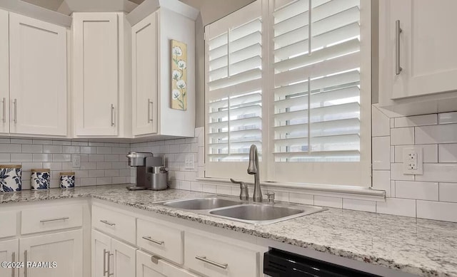 kitchen featuring sink, light stone countertops, tasteful backsplash, dishwashing machine, and white cabinetry