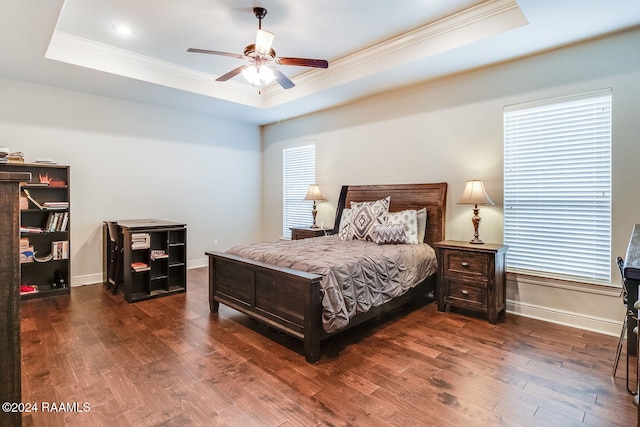 bedroom featuring a raised ceiling, ceiling fan, dark wood-type flooring, and crown molding