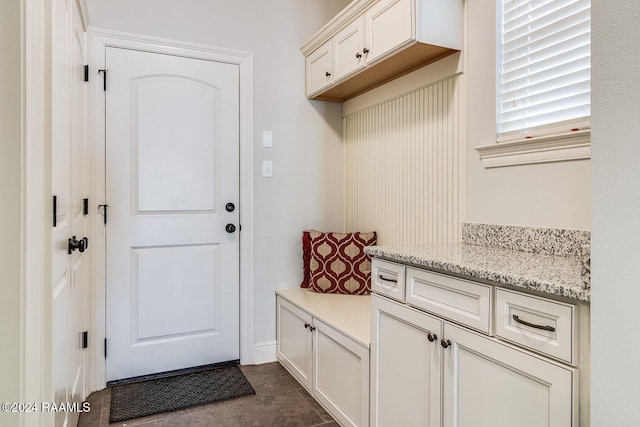 mudroom with dark tile patterned floors