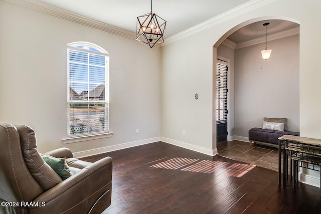 living area featuring a chandelier, dark hardwood / wood-style floors, crown molding, and a healthy amount of sunlight