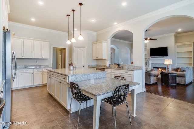 kitchen featuring decorative light fixtures, dark hardwood / wood-style floors, crown molding, and a breakfast bar area