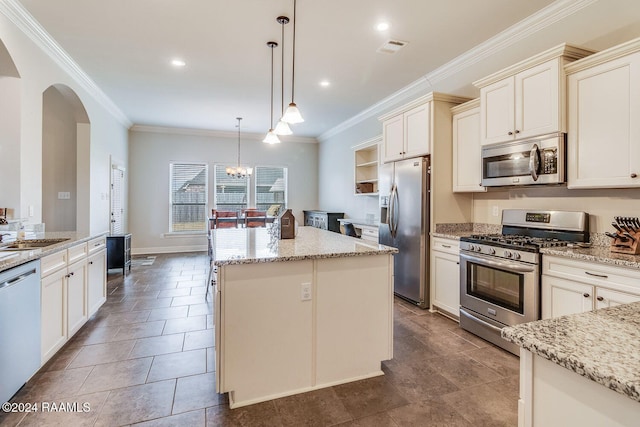 kitchen featuring light stone counters, stainless steel appliances, crown molding, decorative light fixtures, and a center island