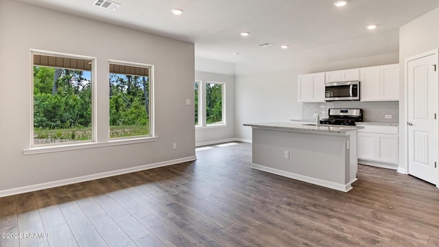 kitchen with white cabinets, a kitchen island with sink, appliances with stainless steel finishes, and dark wood-type flooring