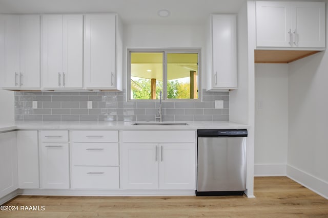 kitchen with stainless steel dishwasher, decorative backsplash, white cabinetry, and sink