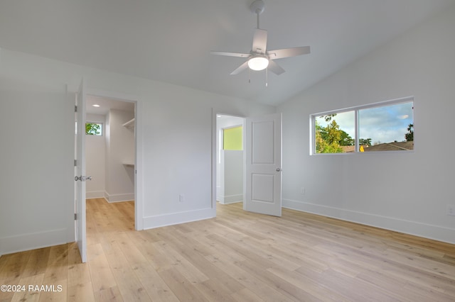 unfurnished bedroom featuring a spacious closet, light hardwood / wood-style flooring, ceiling fan, and lofted ceiling