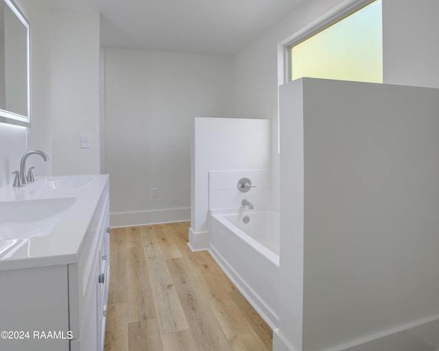 bathroom with hardwood / wood-style flooring, vanity, and a bath