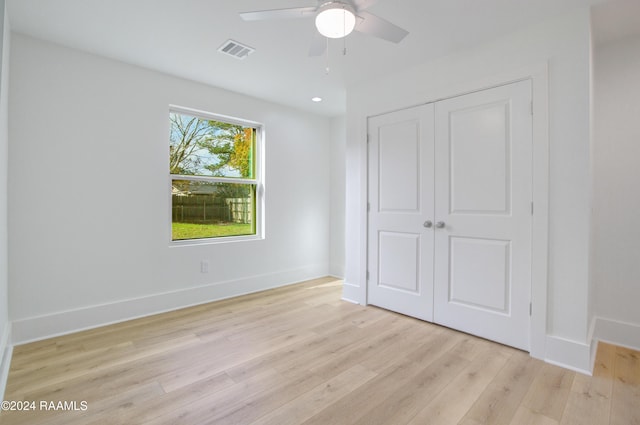 unfurnished bedroom with ceiling fan, light wood-type flooring, and a closet