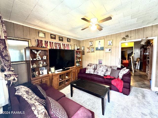 living room featuring carpet flooring, ceiling fan, and wood walls