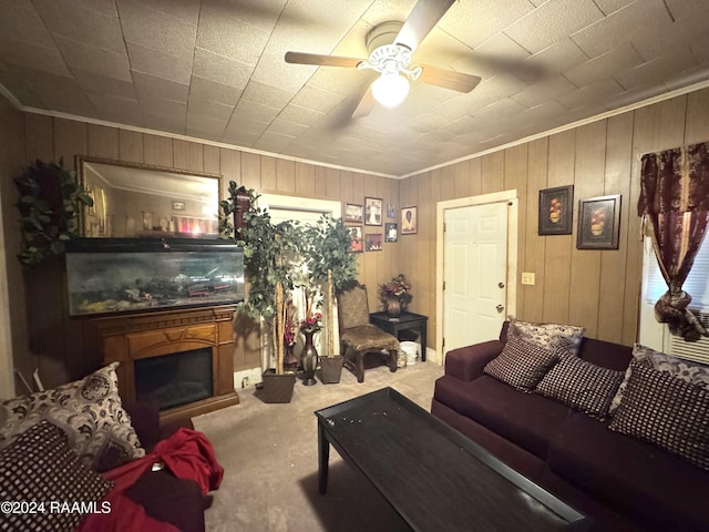 living room featuring ceiling fan, wooden walls, carpet floors, and ornamental molding